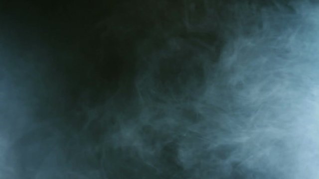 Blue smoke on black background. Cigarette smoke.  Smoke effect. Fog background. Abstract smoke cloud in slow motion. Smoke in studio blue light. Smoke machine