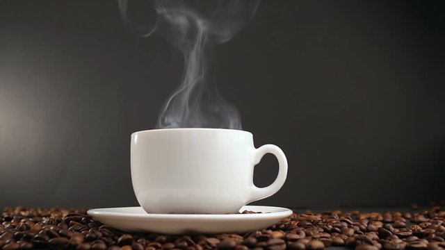 cup with hot drink on roasted coffee beans. dolly shot