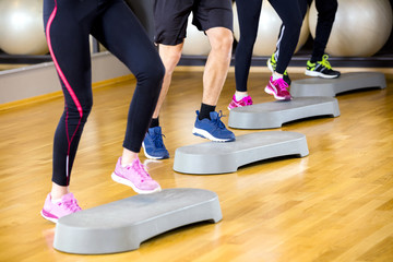 People training with step platform at fitness gym center
