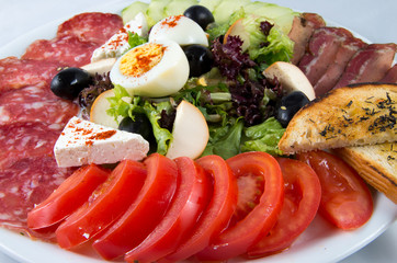 Salad with tomatoes, cucumbers, egg, cheese and sausage.