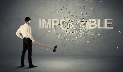 Business man hitting impossible sign with hammer