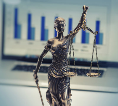 Scales justice with laptop displaying financial information