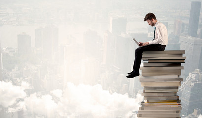 Student in city sitting on stack of books