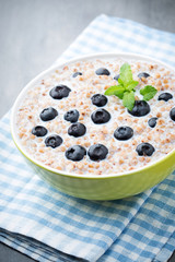Buckwheat porridge in a bowl with mint leaves and blueberries.