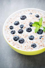 Buckwheat porridge in a bowl with mint leaves and blueberries.