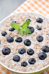 Buckwheat porridge in a bowl with mint leaves and blueberries.
