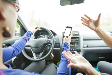 Dangerous female driver reading a text message on her smartphone