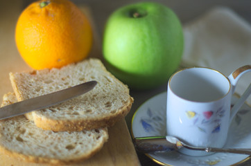 Morning breakfast in natural light on a wooden rustic table. Single coffee cup and fruits