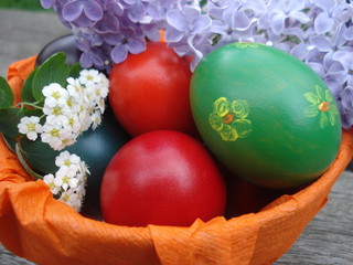 Bowl with painted colorful Easter eggs outdoor on wooden board