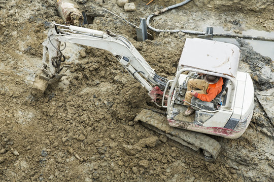 Worker operating digger at construction site