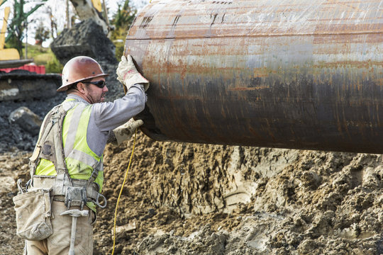 Worker hauling pipe at construction site