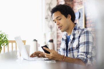 Mixed race man multitasking in coffee shop