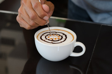 Barista decorate top surface of latte art coffee in white cup