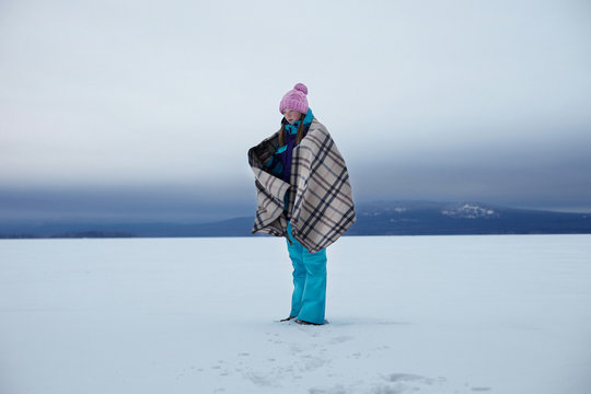 Teenage girl wrapped in blanket in snow