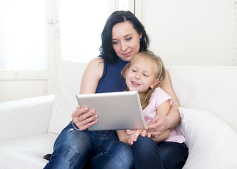 young attractive woman and sweet little blond child holding digital tablet pad watching internet together