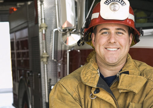 Portrait of firefighter smiling near fire engine