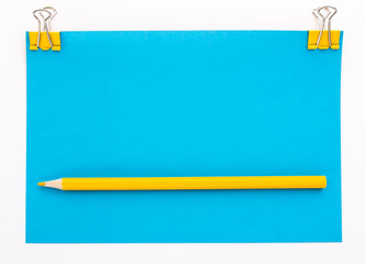 blue piece of paper with yellow paper clips and yellow pencil
