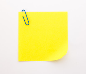 yellow sheet of paper with blue paper clip on a white background