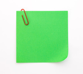 green sheet of paper with red paper clip on a white background