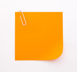 orange sheet of paper with white paper clip on a white background