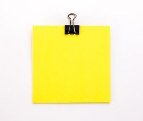 yellow sheet of paper with black paper clip on a white background