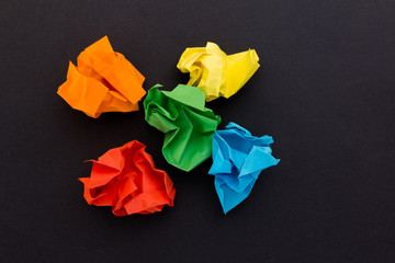 crumpled sheets of colored paper on a black background