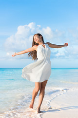 Fototapeta na wymiar Freedom woman feeling free dancing carefree with open arms in elegant white dress at beach sunset. Healthy living Asian girl on summer travel vacation. Success, happiness, mindfulness concept.