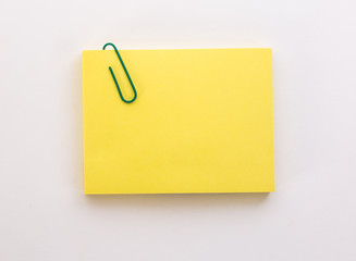 stack of yellow sheets of paper with green paper clip on a white background