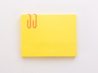 stack of yellow sheets of paper with pink paper clip on a white background