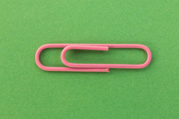 pink paper clip on a green background macro