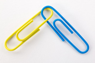 yellow and blue paper clips on a white background macro
