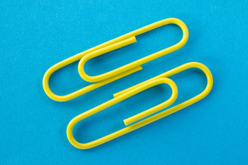 yellow paper clips on a blue background macro