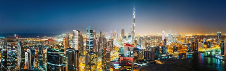 Fototapeta premium Panoramiczny widok z lotu ptaka na duże futurystyczne miasto nocą. Business Bay, Dubaj, Zjednoczone Emiraty Arabskie. Nocna panorama.
