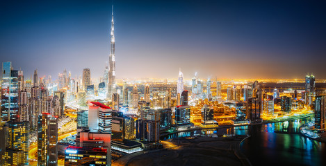 Naklejka premium Aerial panoramic view of a big futuristic city by night. Business bay, Dubai, United Arab Emirates. Nighttime skyline.