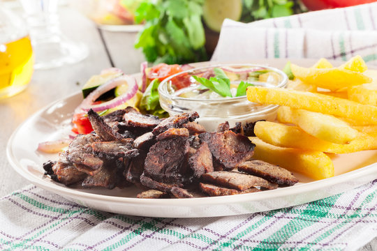Grilled meat with French fries and fresh vegetables
