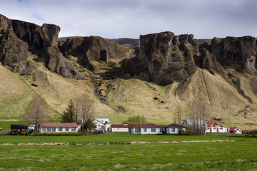 Small village in Iceland with volcanic mountains in background