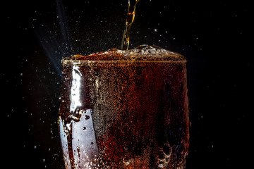 Soda large glass, overflowing glass of soda closeup with bubbles isolated on black background
