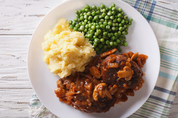 Salisbury steak with potatoes and green peas close-up. Horizontal view from above
