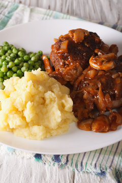 Salisbury steak with mashed potatoes and green peas close-up. vertical

