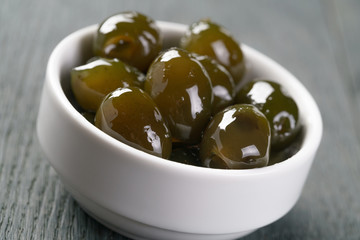 sweet green olives in syrup in bowl, shallow focus