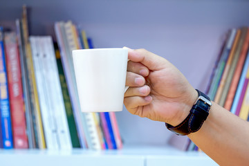 Man holding coffee cup, Books shelf background.jpg