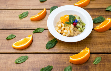 Oatmeal with fresh fruits and honey in small bowls on tray.