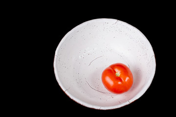 Red tomato on the ceramic bowl prepared for salad