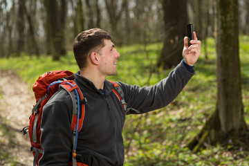 Fototapeta premium Man hiker taking photo with smart phone in forest