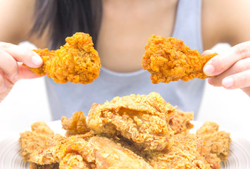 Woman holding and eatting fried chicken in white plate on white