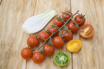 red tomatoes, yellows, greens and spring onions on a wooden table
