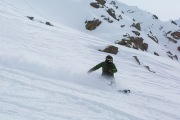 Male snowboarder snowboarding on fresh snow on ski slope on Sunny winter day in the ski resort in...