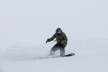 Male snowboarder snowboarding on fresh snow on ski slope on Sunny winter day in the ski resort in...