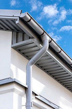 new gray metal rain gutter on house rooftop