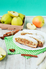 
dessert , apple strudel with cinnamon, sugar and spices on a wooden background   